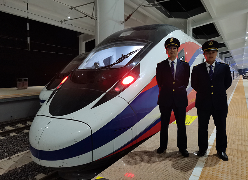 劉銀能（右一）與中國師父鄔俊鴻在動車組前合影。受訪者供圖